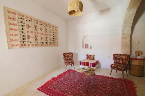 a living room with a table and chairs and a rug at Dar Naël in Houmt Souk