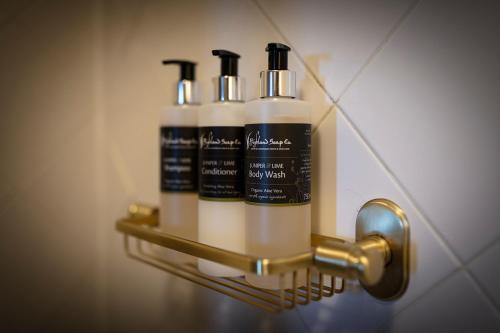 a rack with three shampoo bottles on a wall at Flodigarry Hotel in Staffin