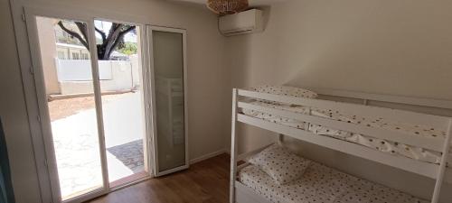 Cette chambre comprend des lits superposés et une porte coulissante en verre. dans l'établissement Maison climatisée avec Grand Jardin - 10 min à pied du Brusc et de sa plage, à Six-Fours-les-Plages