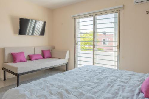 a bedroom with a bed and a window with pink pillows at Amplia casa con 3 habitaciones para hospedaje in Chetumal