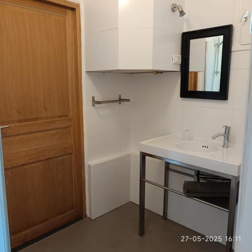 La salle de bains est pourvue d'un lavabo, d'un miroir et d'une porte. dans l'établissement Gîte Donjon, à Fours