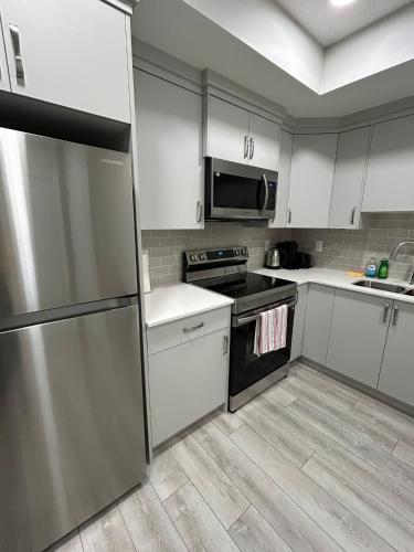 a kitchen with white cabinets and a stainless steel refrigerator at Carssies Place in Calgary