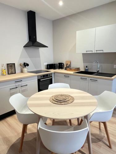 - une cuisine avec une table en bois et des chaises blanches dans l'établissement Appartement Saint-Louis, à Verdun-sur-Meuse