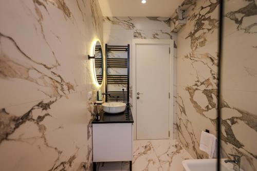 a bathroom with marble walls and a sink at SanPietro Premium Villas in Draçi