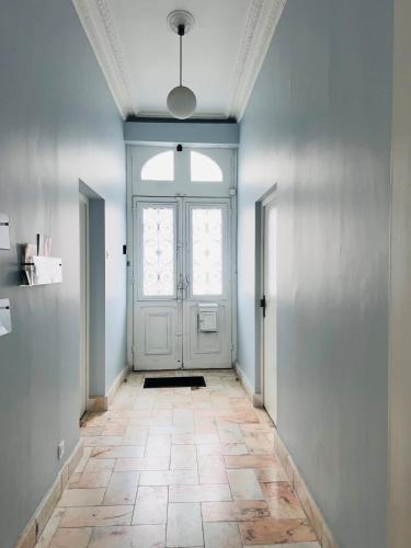 un couloir avec une porte blanche et du carrelage. dans l'établissement Pétale de Liévin, à Liévin