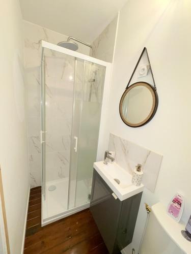 une salle de bain avec une douche, un lavabo et un miroir dans l'établissement Pétale de Liévin, à Liévin