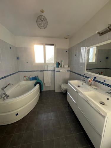 La salle de bains est pourvue d'une baignoire, de deux lavabos et de toilettes. dans l'établissement Évasion à 30 min de Toulouse, à Lagarde