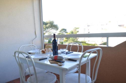 - une table blanche avec des chaises et une bouteille de vin dans l'établissement Test, à Saint-Raphaël