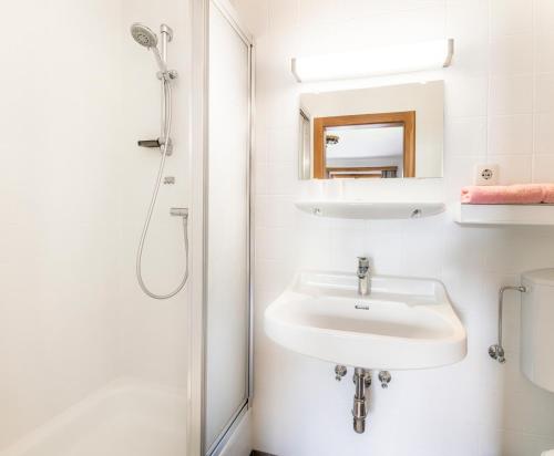 a white bathroom with a sink and a shower at Ferienwohnungen Windischlehen am Zeller See in Maishofen