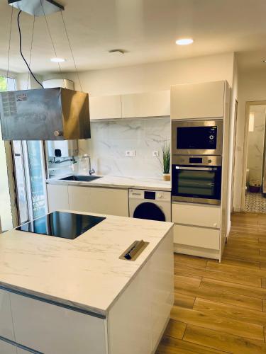 La cuisine est équipée de comptoirs blancs et de plaques de cuisson. dans l'établissement T3 Lumineux & Cosy avec Balcon Escapade by DarBonne, à Narbonne