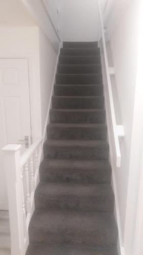 a staircase in a white room with a stair case at Modern Apartment in Southeast London in Plumstead
