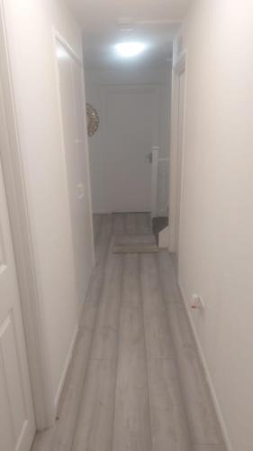an empty hallway with white walls and a wooden floor at Modern Apartment in Southeast London in Plumstead