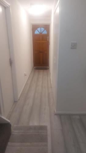 a hallway with a brown door and a wooden floor at Modern Apartment in Southeast London in Plumstead