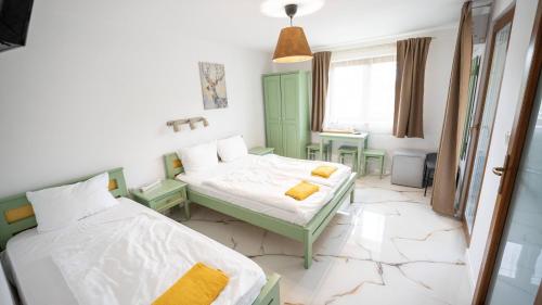 a room with two beds and a table and a window at Airport Károly Centrál in Vecsés