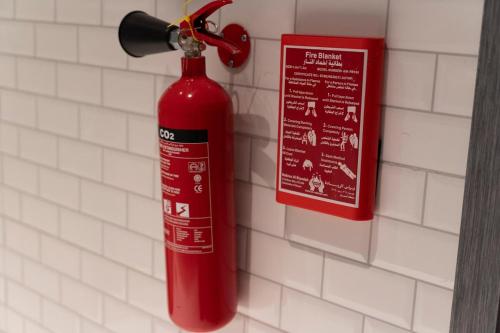 a red fire extinguisher hanging on a wall at Apartment in Alkhoud Muscat in Maţār as Sīb ad Duwalī