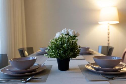 a table with bowls and plates and a vase of flowers at Apartment in Alkhoud Muscat in Maţār as Sīb ad Duwalī