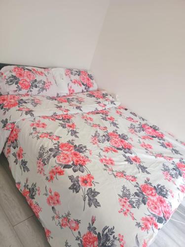 a bed with a black and white blanket with red flowers at Modern Apartment in Southeast London in Plumstead