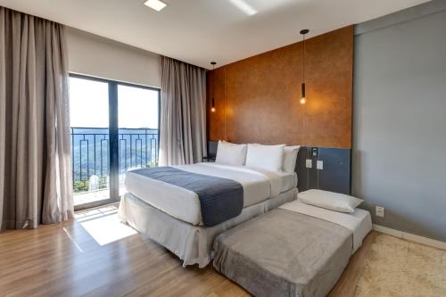 a hotel room with two beds and a large window at Gran Paradiso Campos do Jordão By Ventura OFICIAL in Campos do Jordão