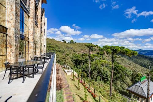 a balcony with tables and chairs on the side of a building at Gran Paradiso Campos do Jordão By Ventura OFICIAL in Campos do Jordão