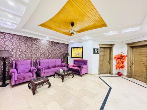 a living room with purple chairs and a ceiling at Alpine lodges in Islamabad