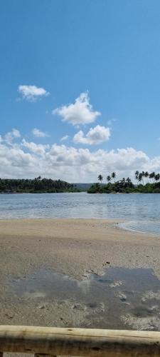 a beach with water and palm trees in the background at Casa Aconchegante in Marechal Deodoro