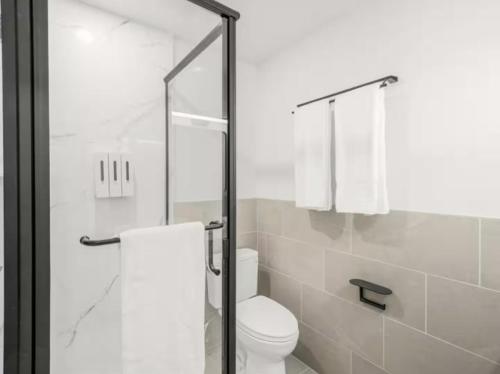 a bathroom with a toilet and a glass shower door at Geary Parkway Motel in San Francisco