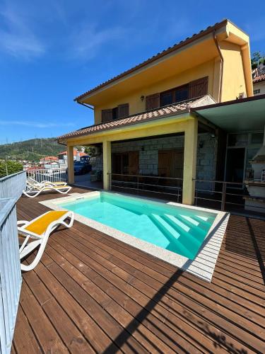 a house with a swimming pool on a wooden deck at Casa Amarela da Caniçada in Vieira do Minho