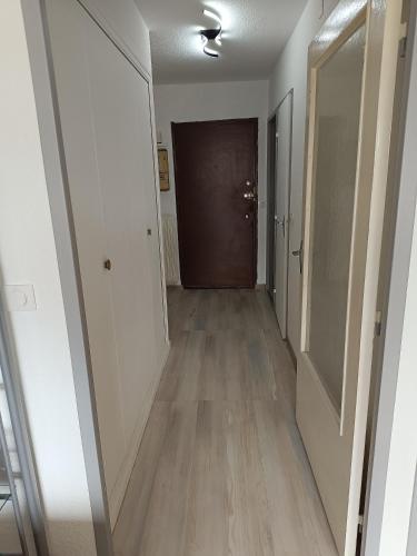 un couloir vide avec une porte marron et du parquet dans l'établissement Dax belle vue, à Dax