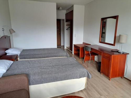 a hotel room with two beds and a desk at Kylpylä-Hotelli, kahden huoneen huoneisto in Ikaalinen