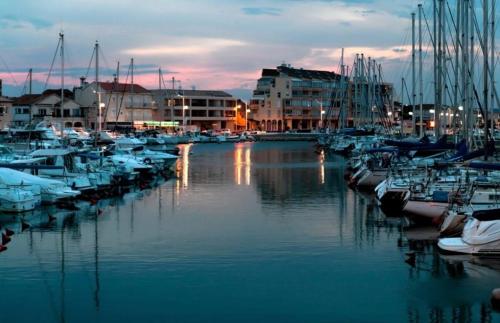 un groupe de bateaux amarrés dans une marina la nuit dans l'établissement **Magnifique Nouveau Bungalow** Village Siblu - Plage - Piscine - Sauna..., à Valras-Plage