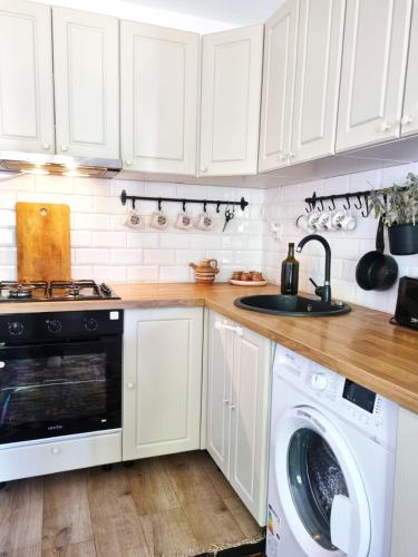 a kitchen with white cabinets and a washer and dryer at Casa LuMINA in Greci