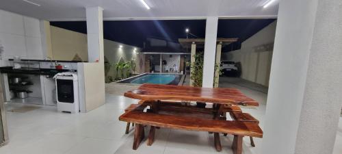 a table and benches in a room with a pool at Casa Aconchegante in Marechal Deodoro