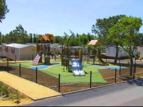 une aire de jeux dans un parc avec un toboggan et des balançoires dans l'établissement **Magnifique Nouveau Bungalow** Village Siblu - Plage - Piscine - Sauna..., à Valras-Plage