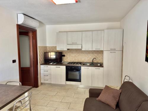 a kitchen with white cabinets and a couch in a room at Residence L'Ancora - Stintino in Stintino