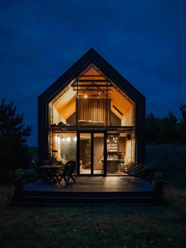 a glass house with a deck at night at Ostoja Narwiańska in Nagórki