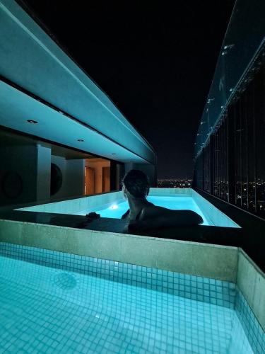 a man laying in a swimming pool at night at With a private terrace in the heart of the city in Mexico City