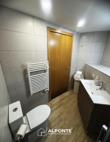 a bathroom with a toilet and a sink and a door at Casa do Galopim in Caminha