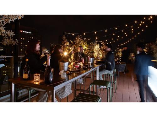 a group of people sitting at tables on a patio at night at THE KNOT HIROSHIMA - Vacation STAY 20577v in Hiroshima