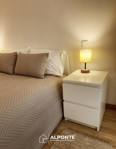 a bed with a night stand with a lamp on it at Casa do Galopim in Caminha