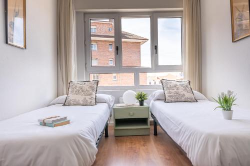 two beds in a room with a window at Soleado apartamento en el centro de la ciudad in Santander