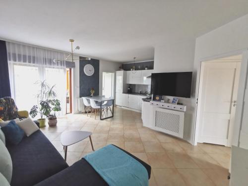 ein Wohnzimmer mit einer blauen Couch und einer Küche in der Unterkunft Apartamenty Wybrzeże Laguna II in Ustronie Morskie