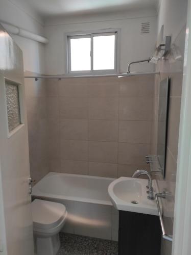 a bathroom with a tub and a toilet and a sink at Depto Centrico en Planta Alta in Bahía Blanca