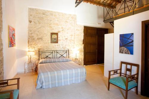 a bedroom with a bed and two chairs at Agriturismo Baglio Fontana in Buseto Palizzolo