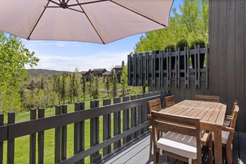 a wooden table and chairs on a deck with an umbrella at Meadow Mountain Vista Multi-level 3br W Hot Tub in Snowmass Village
