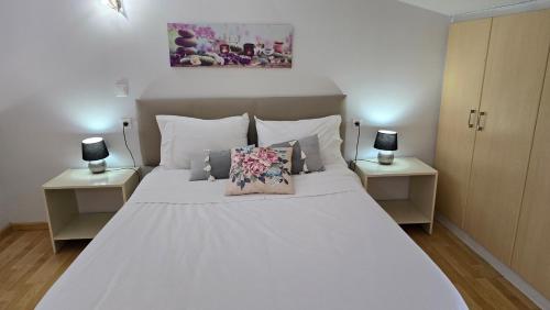 a bedroom with a large white bed with two night stands at Tranquil Apartments Corfu in Kontokali