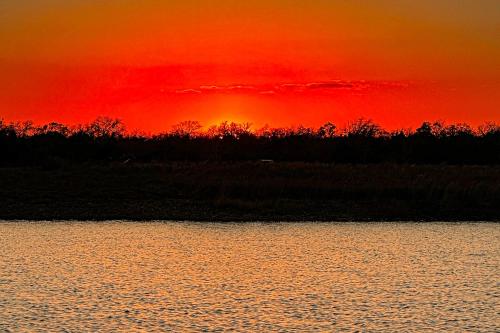 a sunset over a body of water with a red sky at 4 Cabins - Reindeer Ranch at Round Top in Carmine