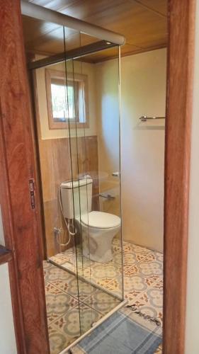 a bathroom with a toilet inside of a glass door at Chalé Refúgio dos Gnomos in Visconde De Maua