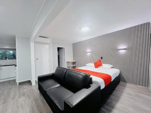 a bedroom with a bed and a black leather couch at Beetham Park Motel in Hamilton