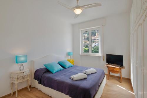 a bedroom with a bed with blue pillows and a window at Porto Santo Stefano Panoramic Penthouse in Porto Santo Stefano