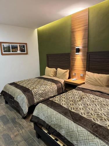 a hotel room with two beds and a desk at Hotel Los Valles Plus in Creel